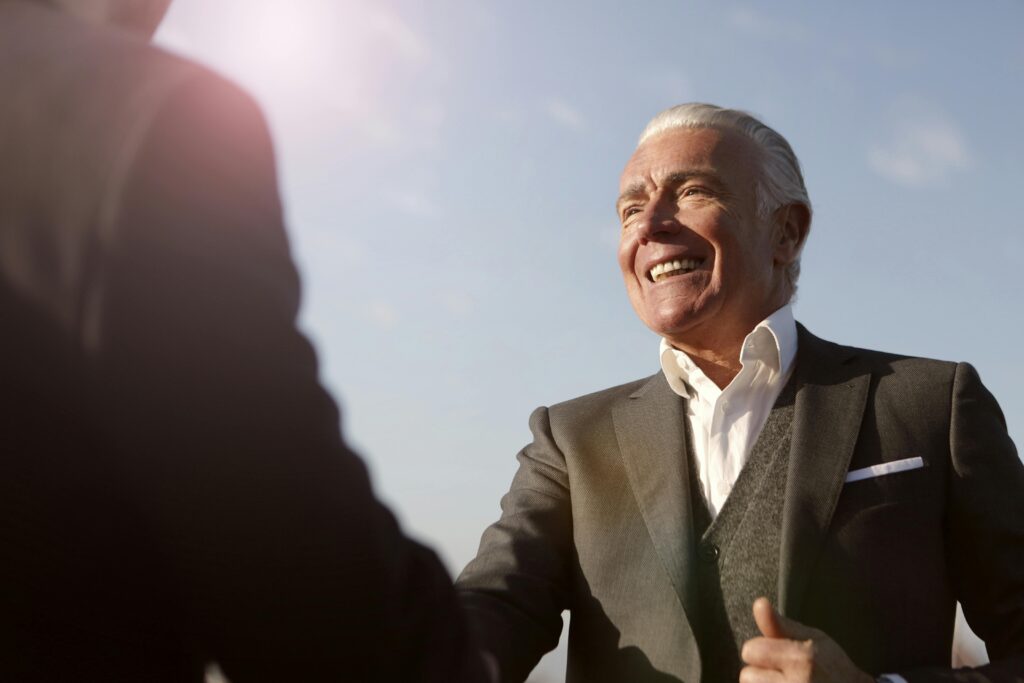 Image of an old man shaking a hand of another person for the blog Leadership Is Not a Prerequisite for Ownership—It's a Journey That Begins With Trust