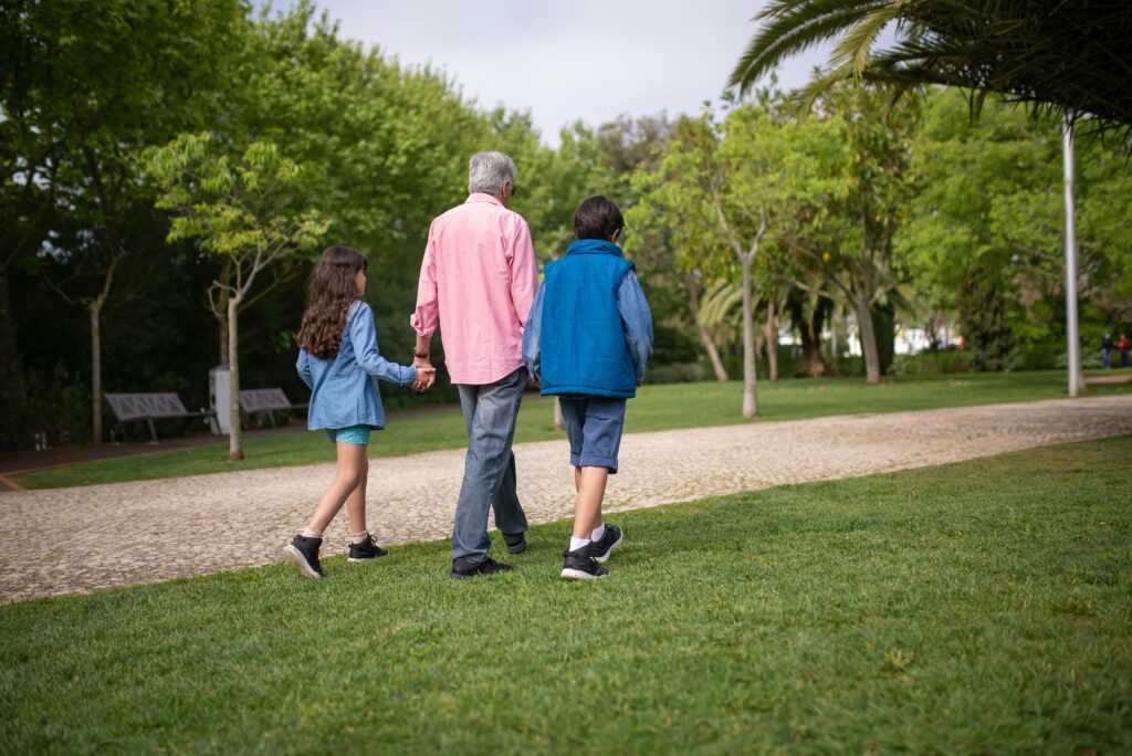 Image of a man walking with children on the grass for the blog, What Does Legacy Really Mean for Business Owners?