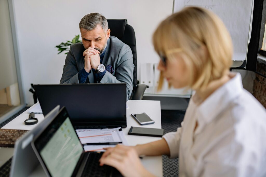 IMage of a man and a woman both looking at their own laptops for the blog: Discover What Are Business Transitions?