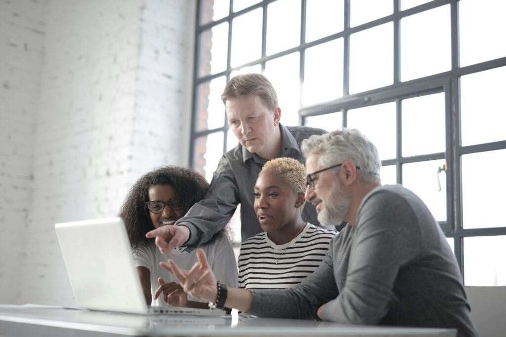 Image of people looking at a laptop screen for the blog, Exit Planning vs. Business Transition: Why the Technical Plan Alone Will Not Get You There