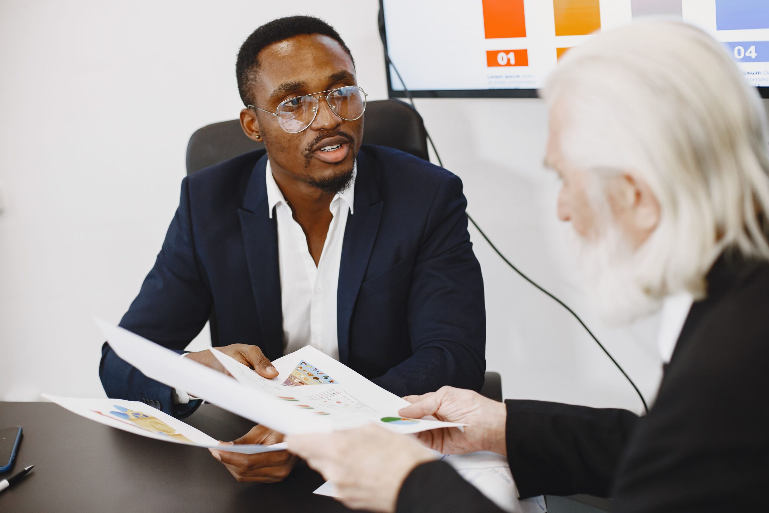 Image of 2 men discussing some documents for the blog: Strategic Business Transition Guide for Retiring Owners