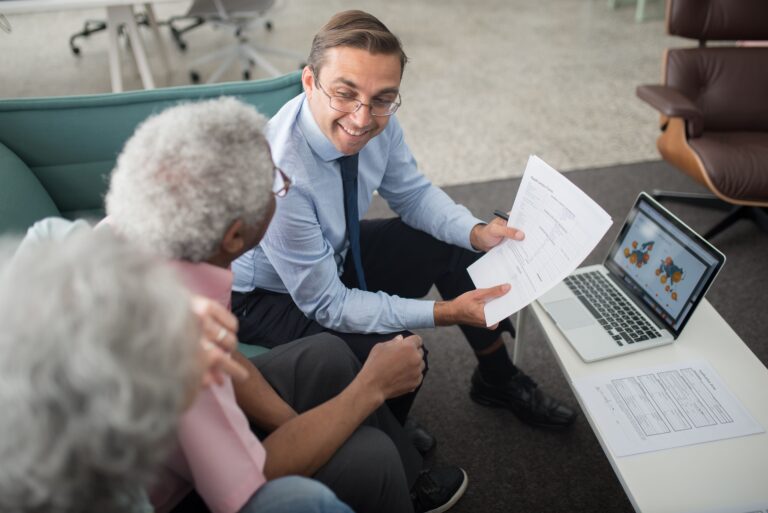 A man talking to two elderly people while holding a document for the blog, What Makes a Transition Strategist Different From Your Attorney and CPA